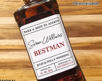 May include: A white label with black text on a brown glass bottle. The label reads "Take a shot to accept Simon Williams Bestman Julie & Will's Wedding Bottle No. 07.08.2024 Distilled in San Diego, CA". The Spirited Labels Personalizable.