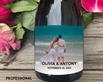 May include: A personalised wine bottle label featuring a photo of a couple on a beach. The label is white with black text that reads "Olivia & Antony" and "November 25, 2023".