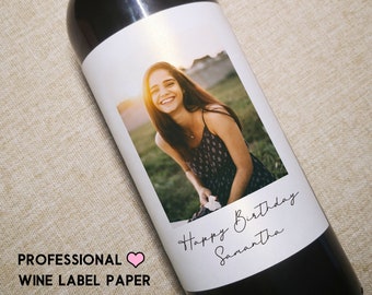 May include: A white wine bottle label with a photo of a person smiling. The label has the text "Happy Birthday Samantha" written in black cursive.