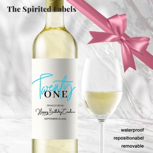 May include: A white wine bottle with a label that says "Twenty ONE" in blue and black script. The label also says "Finally Legal Happy Birthday Carolina September 16, 2021".