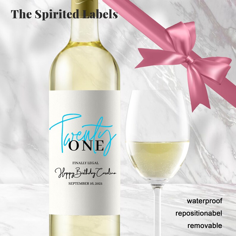 May include: A white wine bottle with a label that says "Twenty ONE" in blue and black script. The label also says "Finally Legal Happy Birthday Carolina September 16, 2021".