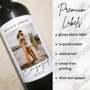 Puede incluir: Una etiqueta de botella de vino blanco con una foto de una pareja bes&aacute;ndose en un muelle. La etiqueta dice "BELLA & JORDAN" y "Engaged 09.10.22". La etiqueta es brillante, reposicionable, impermeable, sin manchas y gruesa.