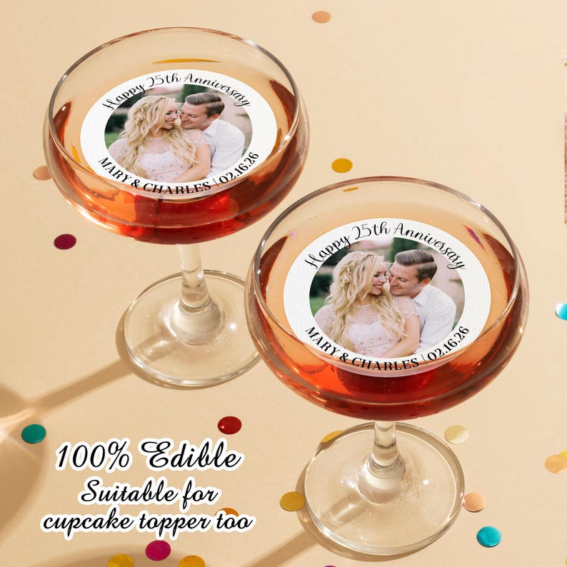 May include: Two clear glass champagne flutes with edible cupcake toppers. The toppers are round and feature a photo of a couple with the text "Happy 25th Anniversary Mary & Charles 02.16.26".