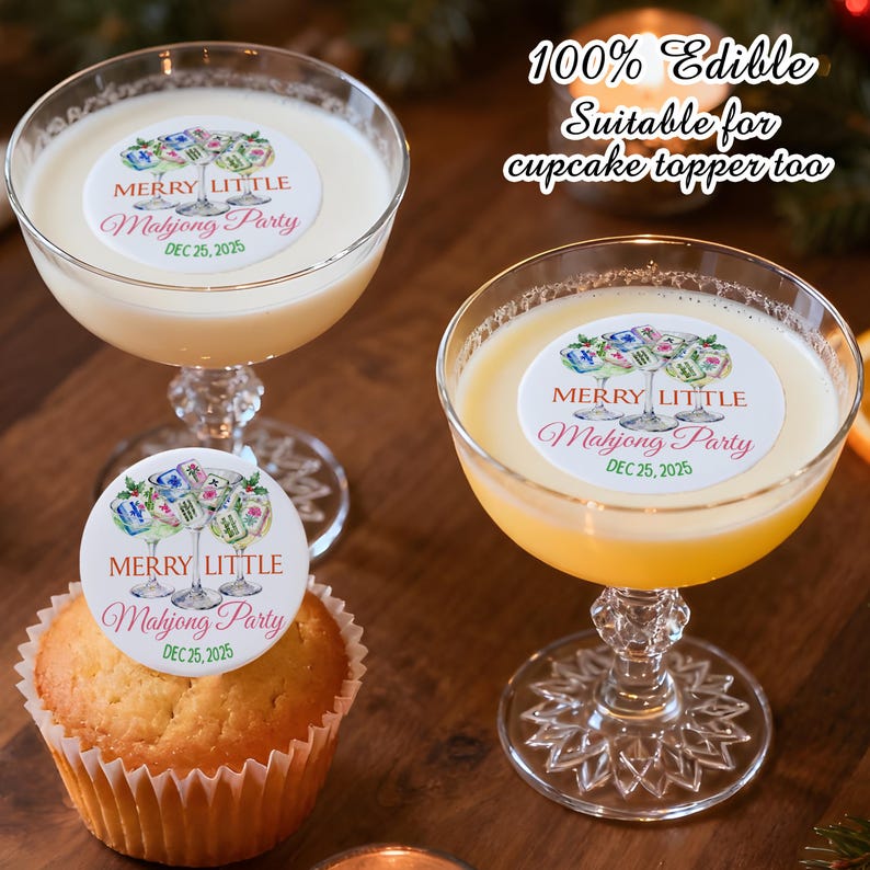 May include: Two coupe glasses filled with cocktails, one with a cupcake. Each drink and the cupcake are topped with a white edible circle featuring a Mahjong Party design. Text reads "MERRY LITTLE Mahjong Party DEC 25, 2025".
