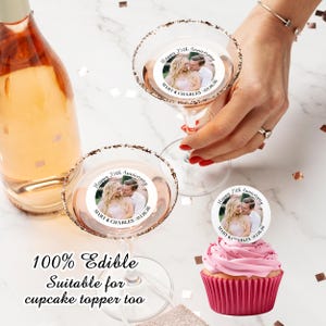 May include: Two clear glass martini glasses with edible cupcake toppers. The toppers are round and white with a photo of a couple and the text "Happy 25th Anniversary Mary & Charles 02.16.26". A pink cupcake with a topper is also shown.