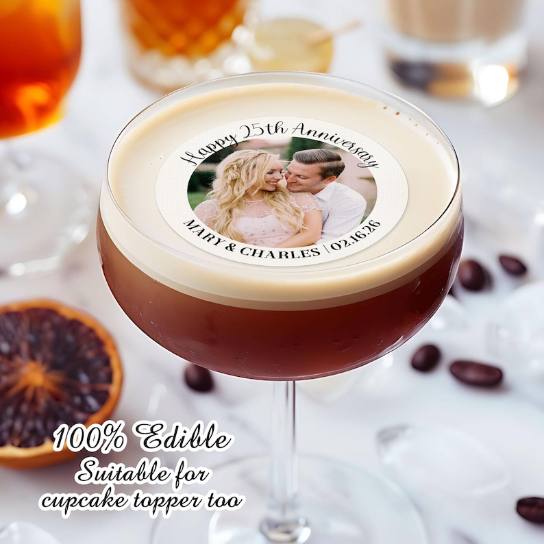 May include: A white round edible cake topper with a photo of a couple and the text "Happy 25th Anniversary Mary & Charles 02.16.26". The topper is on top of a brown drink in a martini glass. The text "100% Edible Suitable for cupcake topper too" is below the glass.
