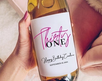 May include: A white wine bottle with a label that says "Thirty ONE" in pink and black lettering. The label also says "Happy Birthday Caroline" and "SEPTEMBER 16, 2021".