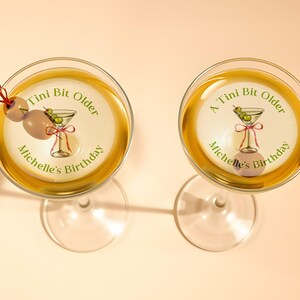 May include: Two martini glasses with a sticker on each that says "A Tini Bit Older Michelle's Birthday" with a martini glass and olives on the sticker.