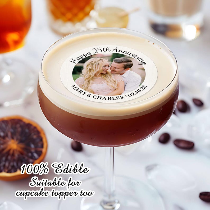 May include: A white round edible cake topper with a photo of a couple and the text "Happy 25th Anniversary Mary & Charles 02.16.26". The topper is on top of a brown drink in a martini glass. The text "100% Edible Suitable for cupcake topper too" is below the glass.
