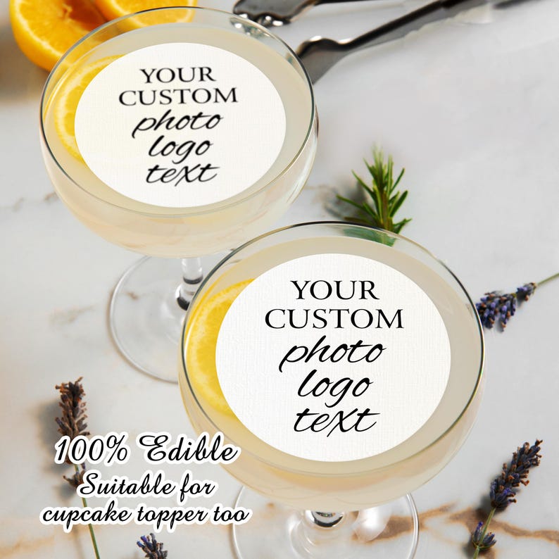 May include: Two white round edible cupcake toppers with the text "YOUR CUSTOM photo logo text" on each. The toppers are on top of clear glass cocktail glasses with a lemon slice in each glass. The text "100% Edible Suitable for cupcake topper too" is below the glasses.