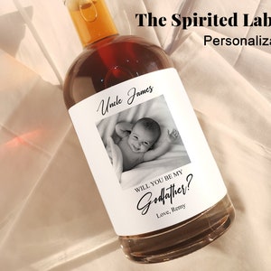 May include: A white label with black text and a photo of a baby. The text reads "Uncle James" and "Will you be my Godfather? Love, Remy".