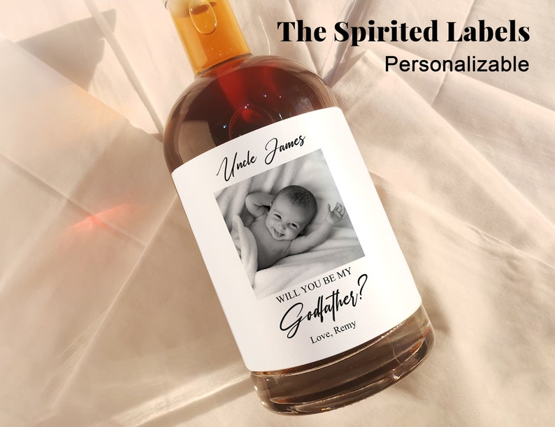 May include: A white label with black text and a photo of a baby. The text reads "Uncle James" and "Will you be my Godfather? Love, Remy".
