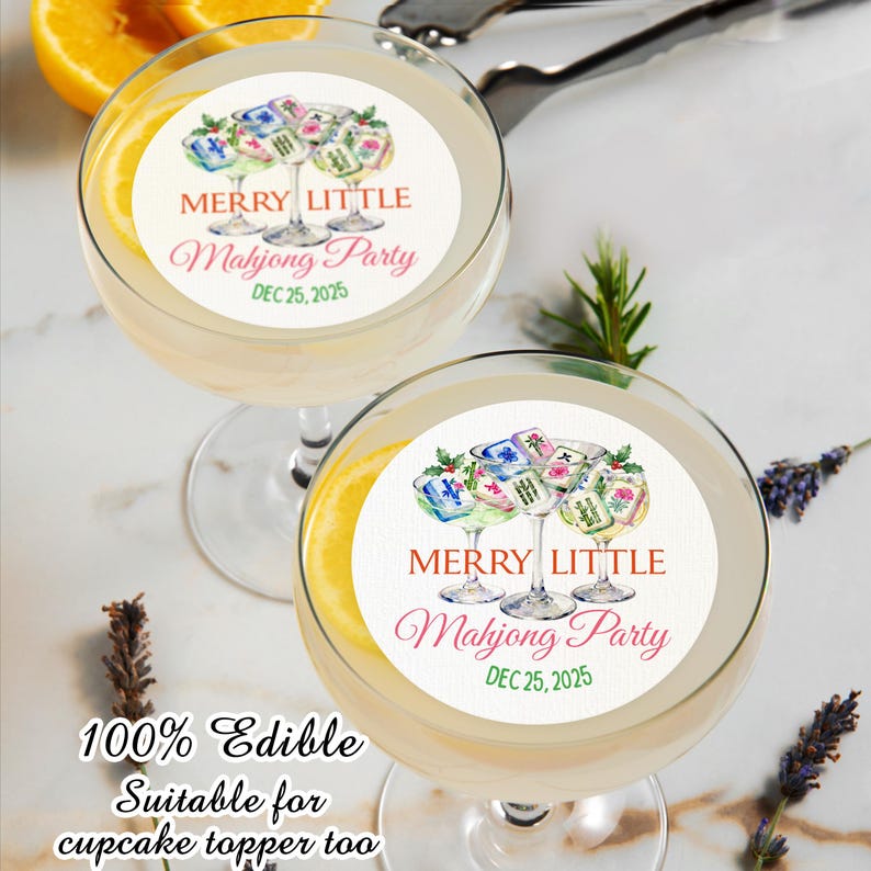 May include: Two cocktail glasses with a lemon slice and a white edible topper. The topper reads "MERRY LITTLE Mahjong Party DEC 25, 2025" with Mahjong tiles. The text "100% Edible Suitable for cupcake topper too" is also visible.