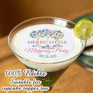 May include: A cocktail in a martini glass with a lime wedge. The drink has a white foamy top and a green base. A white circular edible cupcake topper features the text "Merry Little Mahjong Party" and "Dec 25, 2025".
