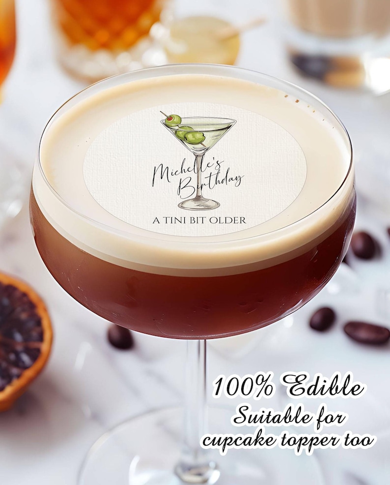 May include: A round edible image of a martini glass with olives, with the text "Michelle's Birthday A Tini Bit Older" printed on it. The image is on top of a brown drink in a martini glass. 100% Edible. Suitable for cupcake topper too.