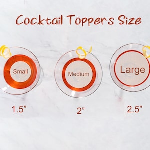 May include: Three cocktail toppers in different sizes: small (1.5 inches), medium (2 inches), and large (2.5 inches). Each topper is a round, orange-colored disc with a white circle in the center.