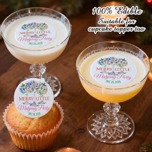 May include: Two coupe glasses filled with cocktails, one with a cupcake. Each drink and the cupcake are topped with a white edible circle featuring a Mahjong Party design. Text reads "MERRY LITTLE Mahjong Party DEC 25, 2025".