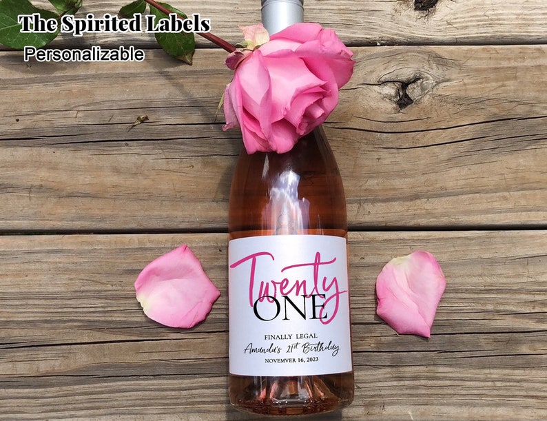 May include: A pink wine bottle with a white label that says "Twenty One" in pink script. The label also says "Finally Legal" and "Amanda's 21st Birthday" with the date "November 16, 2023".