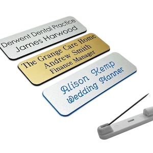 May include: Three silver, gold and white name tags with black text. The text on the silver tag reads "Derwent Dental Practice James Harwood". The text on the gold tag reads "The Grange Care Home Andrew Smith Finance Manager". The text on the white tag reads "Alison Kemp Wedding Planner".