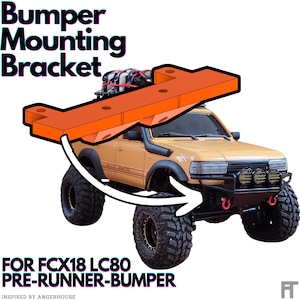 May include: Orange plastic bumper mounting bracket for an FCX18 LC80 pre-runner bumper. The bracket is shown above a yellow toy truck with black tyres.