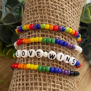 May include: Four colorful beaded bracelets with the words "LOVE WINS" spelled out in white beads.