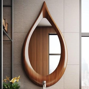 Pode incluir: Um espelho de madeira em forma de gota com um acabamento castanho quente e polido. A moldura do espelho tem um design suave e curvo, e a superfície refletora é visível dentro da moldura. O espelho é montado numa parede azulejada.