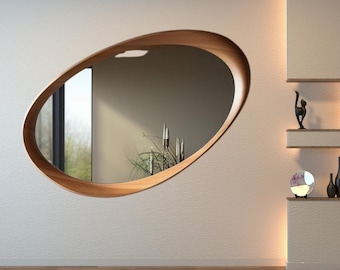 Peut inclure: Un miroir ovale encadré de bois, fixé sur un mur blanc texturé. Le miroir reflète une fenêtre et une décoration intérieure. Le cadre est en bois naturel. La pièce a une esthétique minimaliste. Dimensions: environ 100 cm de long et 60 cm de large.