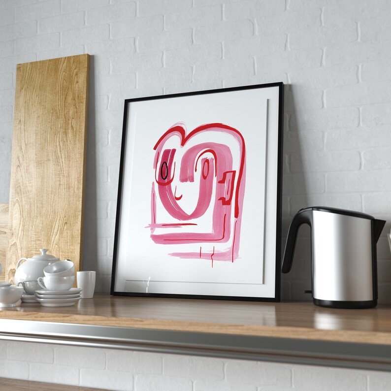 May include: A framed abstract painting with a pink and red design. The painting is in a black frame and is hanging on a white brick wall.