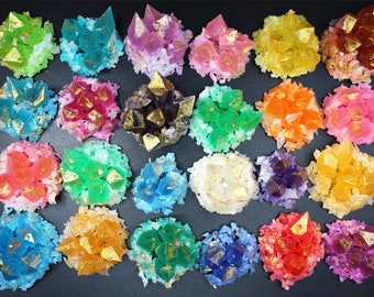 May include: Assortment of 25 colourful crystal-shaped soaps with gold accents. Each soap is shaped like a cluster of crystals and is surrounded by white flakes.