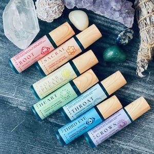 May include: Seven small glass bottles with wooden caps, each containing a different colored liquid. The bottles are labeled with the names of the seven chakras: Root, Sacral, Solar Plexus, Heart, Throat, Third Eye, and Crown. Each label also includes a symbol representing the corresponding chakra.