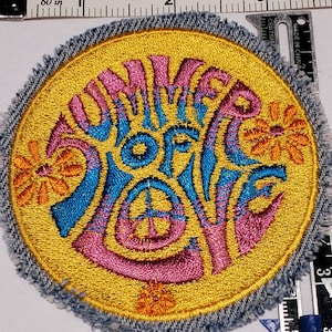May include: A yellow, blue, and pink embroidered patch with the words "Summer of Love" in a psychedelic font. The patch is surrounded by a denim border.