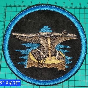 May include: A circular patch with a black background and a blue border. The patch features a detailed illustration of an anvil with a hammer and other tools. The patch measures 4.75 inches by 4.75 inches.