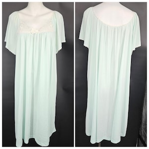 May include: A light green nightgown with short, flutter sleeves. The neckline and sleeves are trimmed with a delicate, scalloped lace. The bodice features a white lace insert with a small floral accent. The nightgown is displayed on a mannequin.