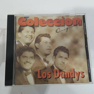 May include: A music CD in a clear plastic jewel case featuring a sepia-toned cover image of four men in suits and bow ties. The text on the cover reads Coleccion Original and Los Dandys in bold orange lettering against a light brown background.