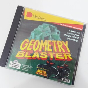 Puede incluir: Una caja de CD-ROM de Geometry Blaster para Windows y Macintosh. La portada presenta una estructura geométrica verde, texto rojo que dice Geometry Blaster y el texto: Covers an entire year of high school geometry! From the makers of Math Blaster.