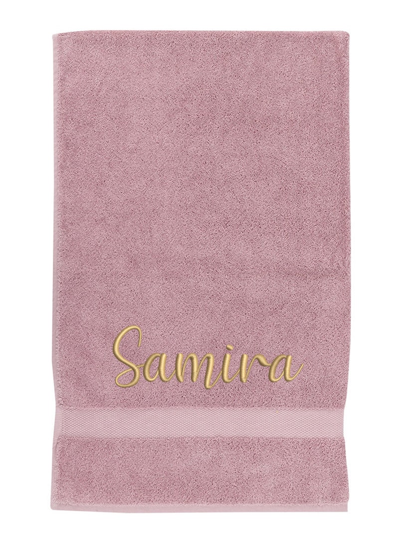May include: A soft, pink towel with the name "Samira" embroidered in gold thread.