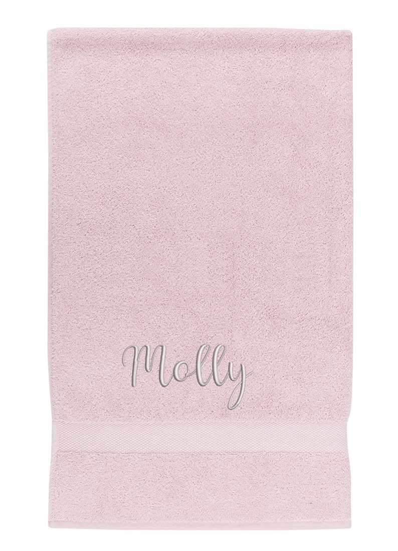 May include: A pink bath towel with the name "Molly" embroidered in white.