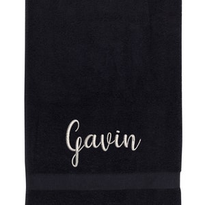 May include: Black bath towel with a white embroidered name "Gavin" in a cursive font.