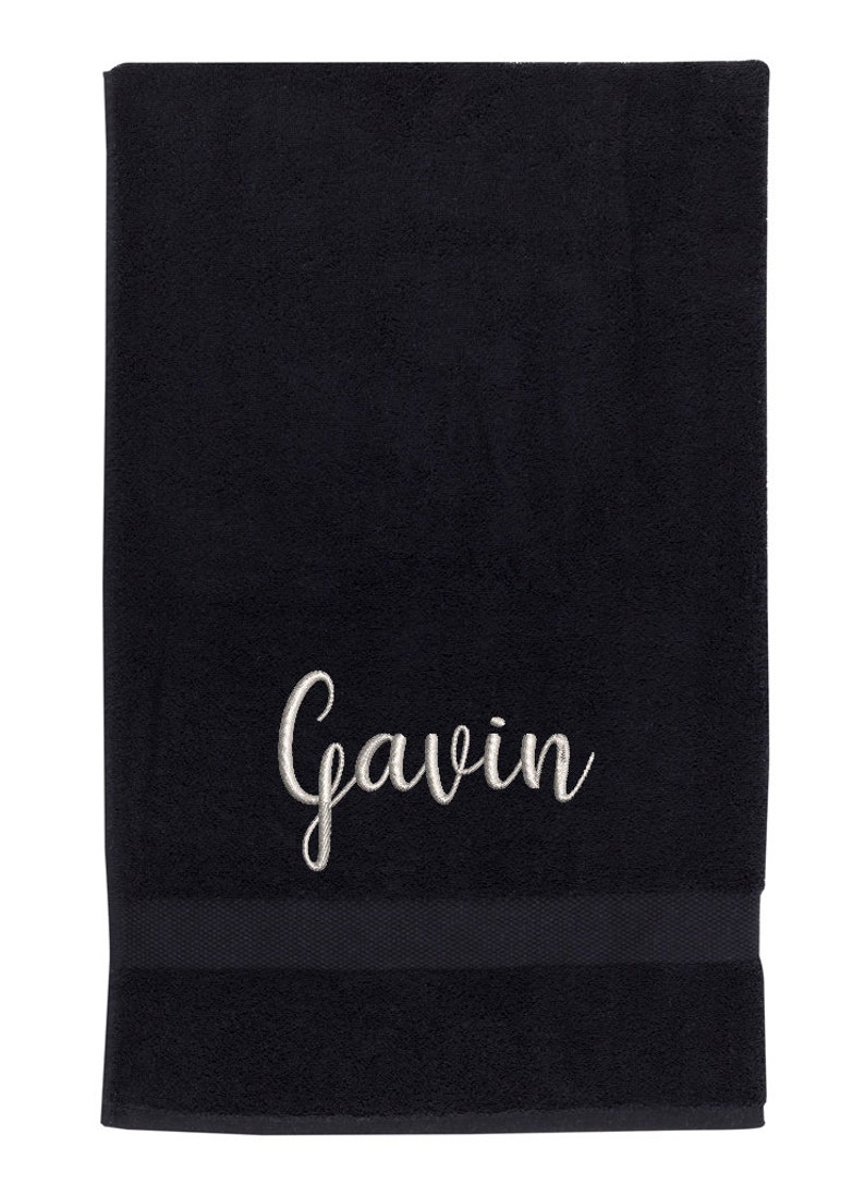 May include: Black bath towel with a white embroidered name "Gavin" in a cursive font.