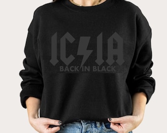 May include: Black sweatshirt with a black graphic of the text "AC/DC" in a bold, stylized font with a lightning bolt in the middle. The text below the graphic says "Back in Black".
