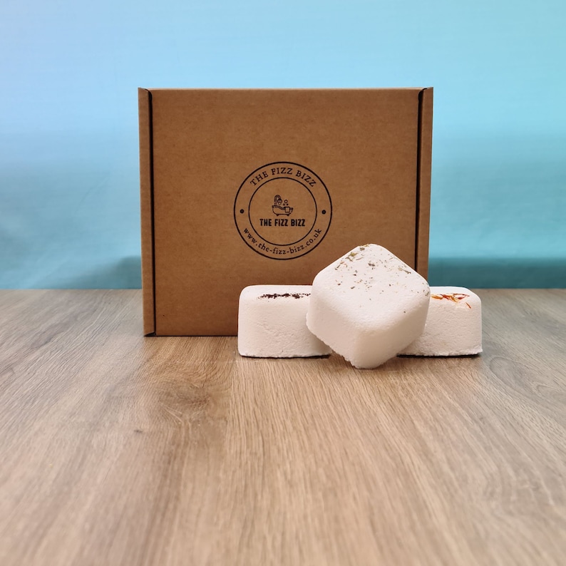 3 of our shower steamers (Hangover, Anti-Anxiety, and Kick Start) artfully arranged in front of their presentation box. For information on their scents refer to scent page. For information on their size use the dimension page.