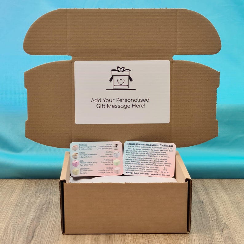 The open gift box showing the personalisation option and the included shower steamer scent and selection card against a blue background