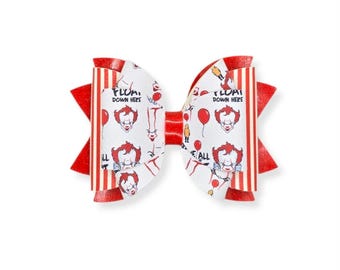 May include: A red and white bow with a horror movie theme. The bow features a repeating pattern of a clown face, balloons, and the text "FLOAT DOWN HERE". The bow has red and white striped accents.