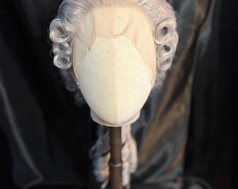 Könnte beinhalten: Eine silbergraue Perücke mit einem Spitzenfront und zwei großen Locken auf jeder Seite. Die Perücke befindet sich auf einem Mannequin-Kopf.