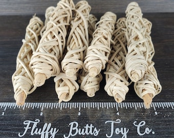 May include: A close-up of a group of 10 natural woven, beige,  dog chew toys. The chew toys are arranged in a row on a wooden surface. A ruler with the text "Fluffy Butts Toy Co." is in the foreground.