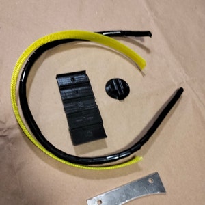 May include: A set of black and yellow cable management components, including a cable tie, a cable clip, a small black knob, and a metal bracket.