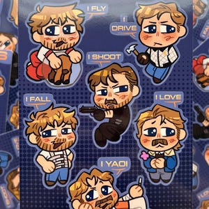Op de afbeelding: Een rechthoekig stickervel met de titel THE GOSLINGS met zes chibi-stijl illustraties van een man met bruin haar en een baard. Elk personage is gekoppeld aan een tekstballon met de tekst I FLY, I DRIVE, I SHOOT, I FALL, I LOVE of I YAOI, tegen een donkerblauwe achtergrond met een subtiel rasterpatroon.