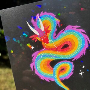 May include: A rainbow dragon with pink accents on a black background with iridescent glitter. The dragon is curled up with its head facing the viewer.