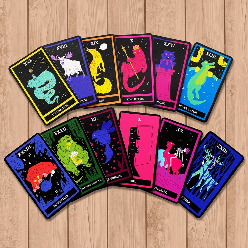 May include: A set of 12 illustrated playing cards with black backgrounds and colorful illustrations. The cards feature a variety of creatures, including a tatzelwurm, a king otter, a sewer gator, a swamp monster, a ghost, and a deer. The cards are numbered from 0 to XLIII.