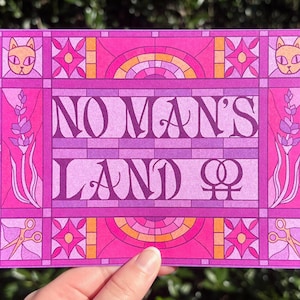 Op de afbeelding: Een roze en paarse kunstprint met de tekst "NO MAN'S LAND" en een vrouwelijk symbool. Het ontwerp bevat kattengezichten, lavendel, scharen en geometrische vormen, die doen denken aan glas-in-lood.